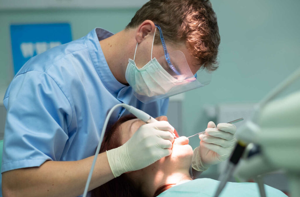 A male dentist is using a scaler in removing dental plaque. Cleaning the teeth before whitening.