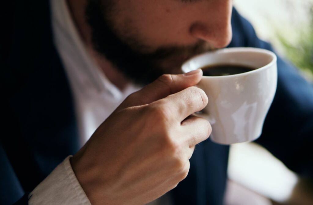 A woman smelling a cup of coffee.