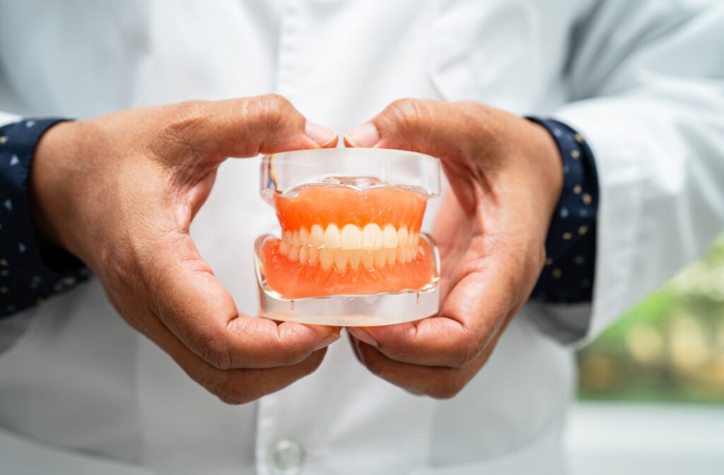 A dentist holds a pair of dentures in his hands.