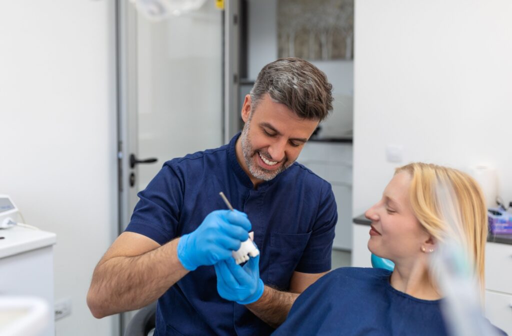 A dentist uses a model of their patient's teeth to discuss treatment options for filling their gap.
