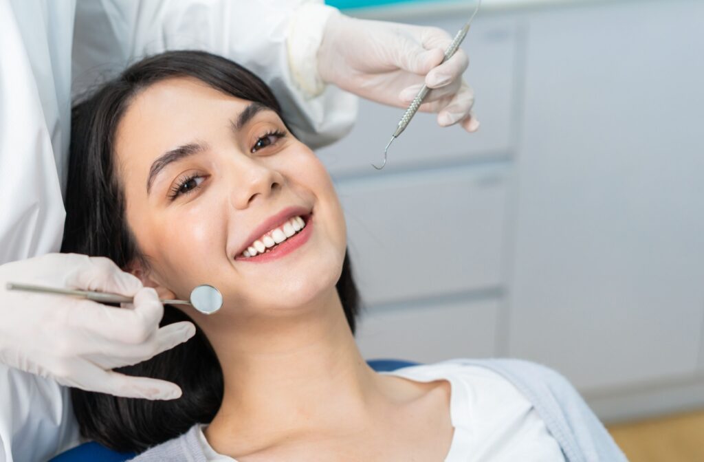 A smiling patient lying in a dentist chair during a dental exam.
