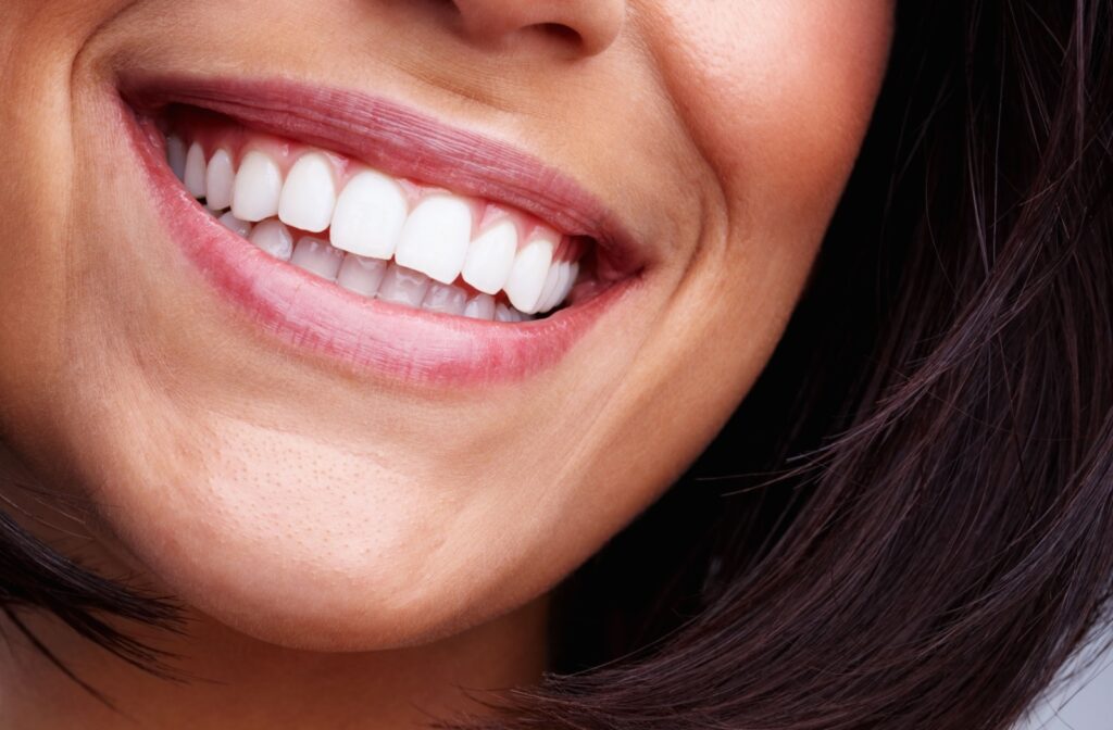 Close-up of a woman smiling, showing healthy white teeth.