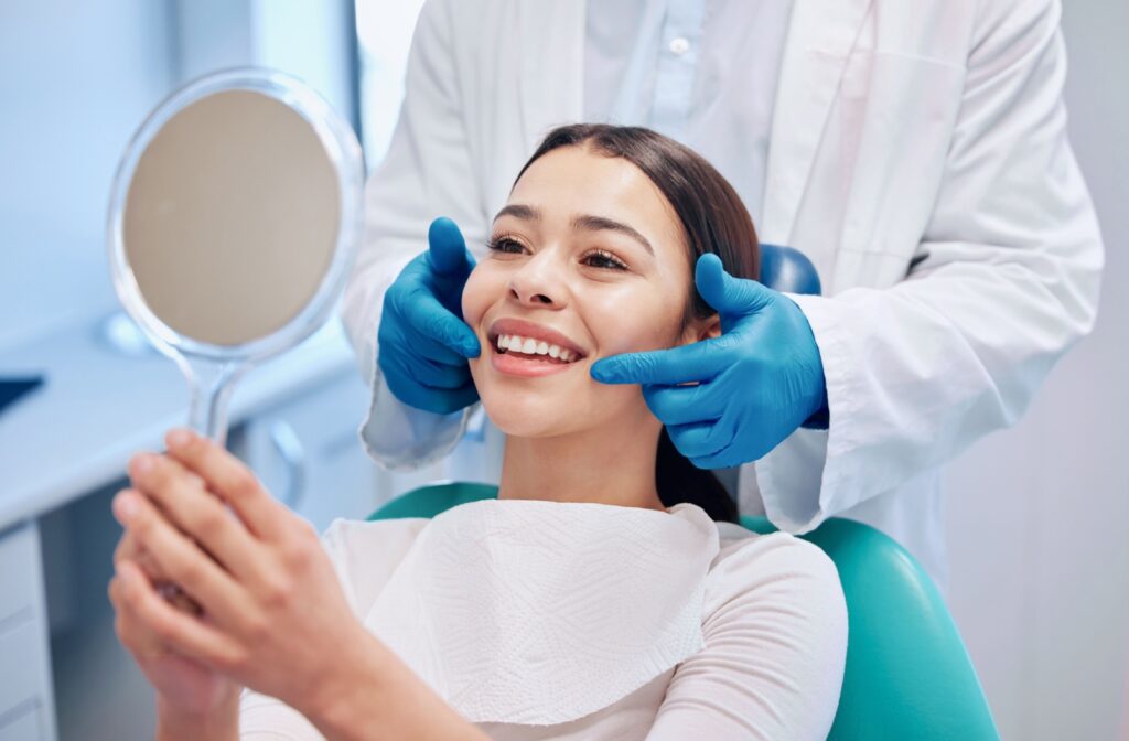 Woman smiling while looking in a mirror during a dental checkup.